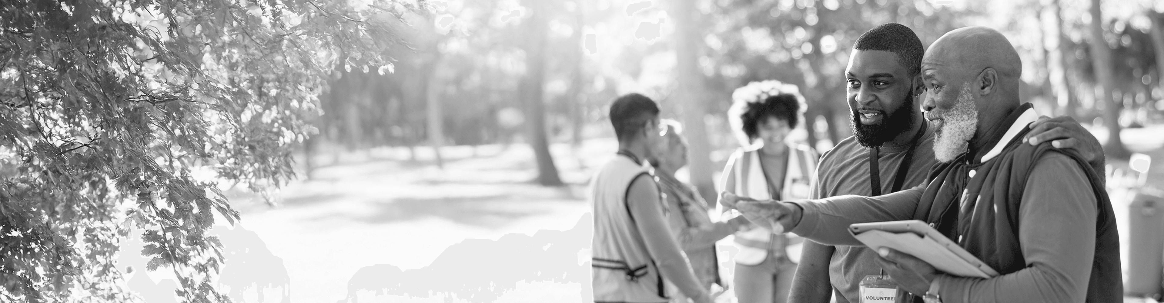 Young man with arm around an older gentleman as they both look toward something while conversing