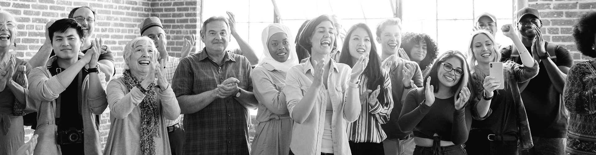 A diverse group of people facing the camera while clapping and cheering